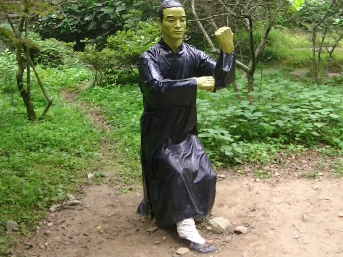 Martial arts statue in fighting stance among garden greenery
