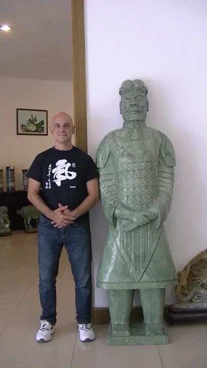 Tony Garcia standing beside a terracotta warrior replica