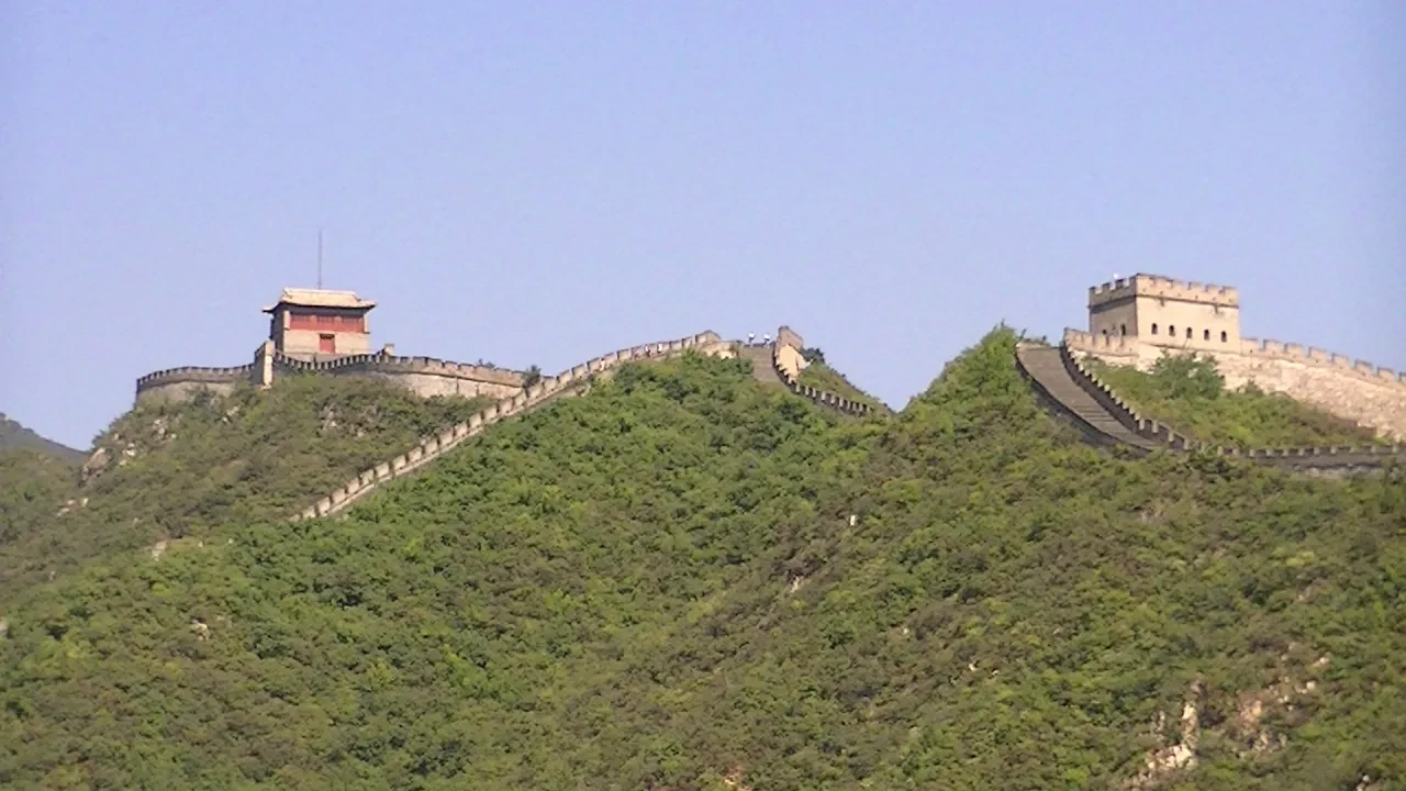 The Great Wall stretching across two green hilltops under a clear blue sky