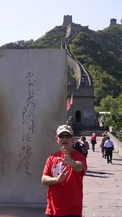 Tony Garcia at the Great Wall of China beside a calligraphy stone monument